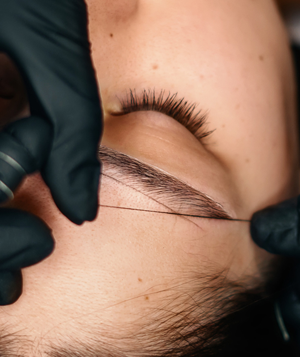 Kobieta na zabiegu makijażu permanetnego brwi w trakcie mierzenia odległości i dopracowywania kształtu